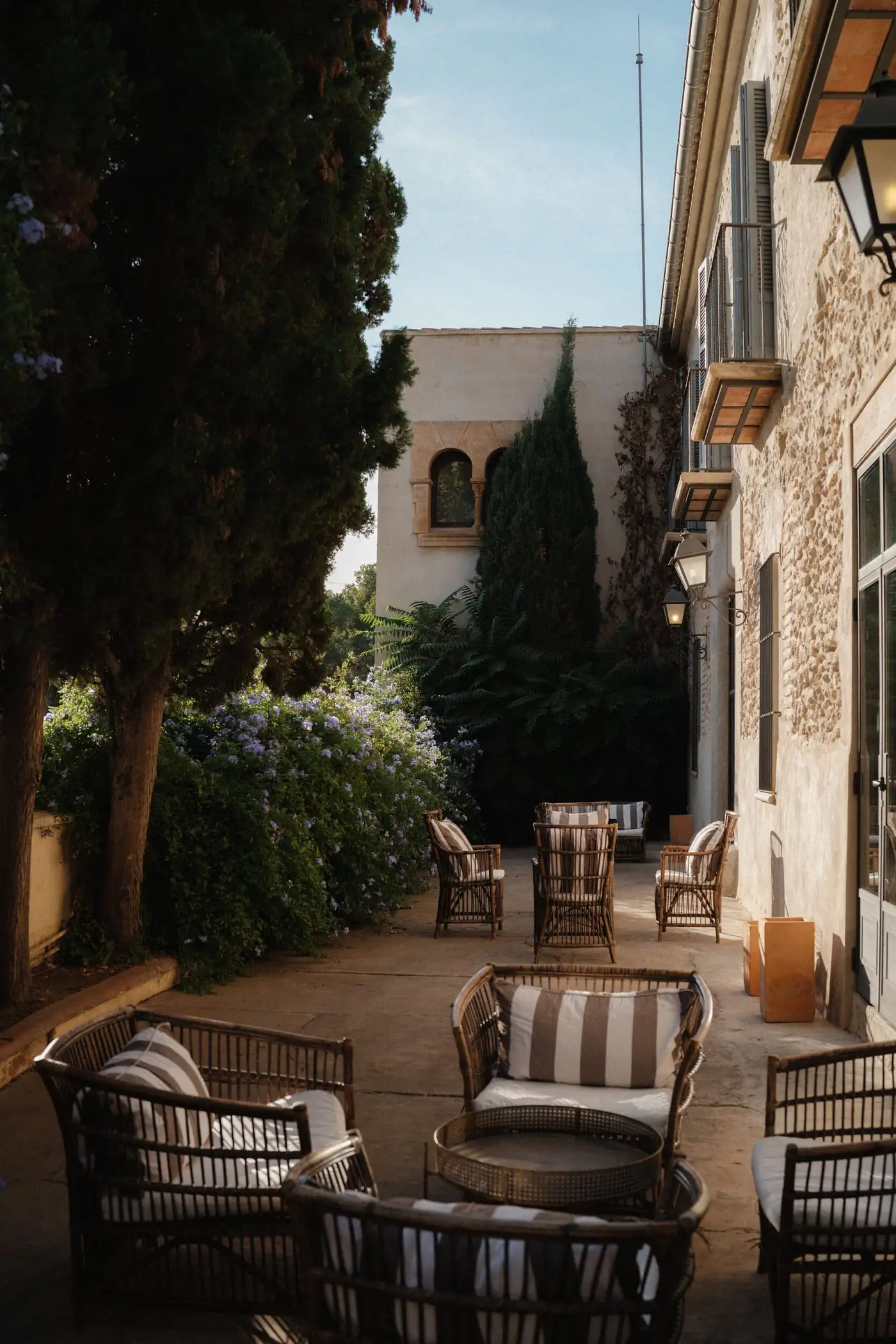 Patio de finca en Mallorca con asientos de mimbre y jardín mediterráneo